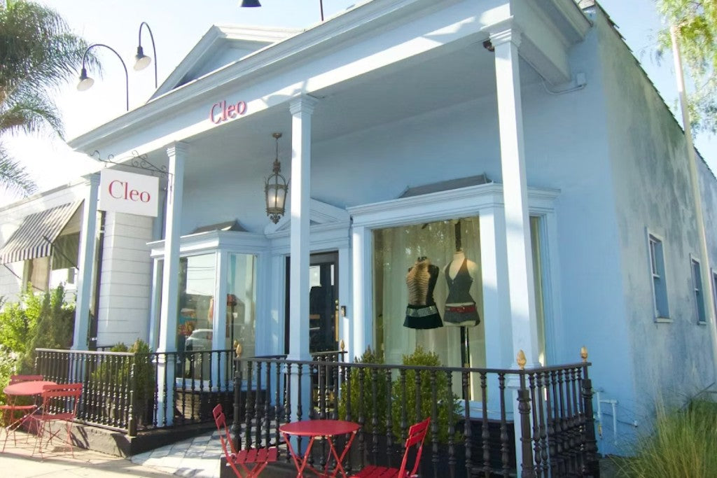 The Cleo storefront, a pale blue 1939 building with a columned porch and red bistro tables on West Third Street, Los Angeles